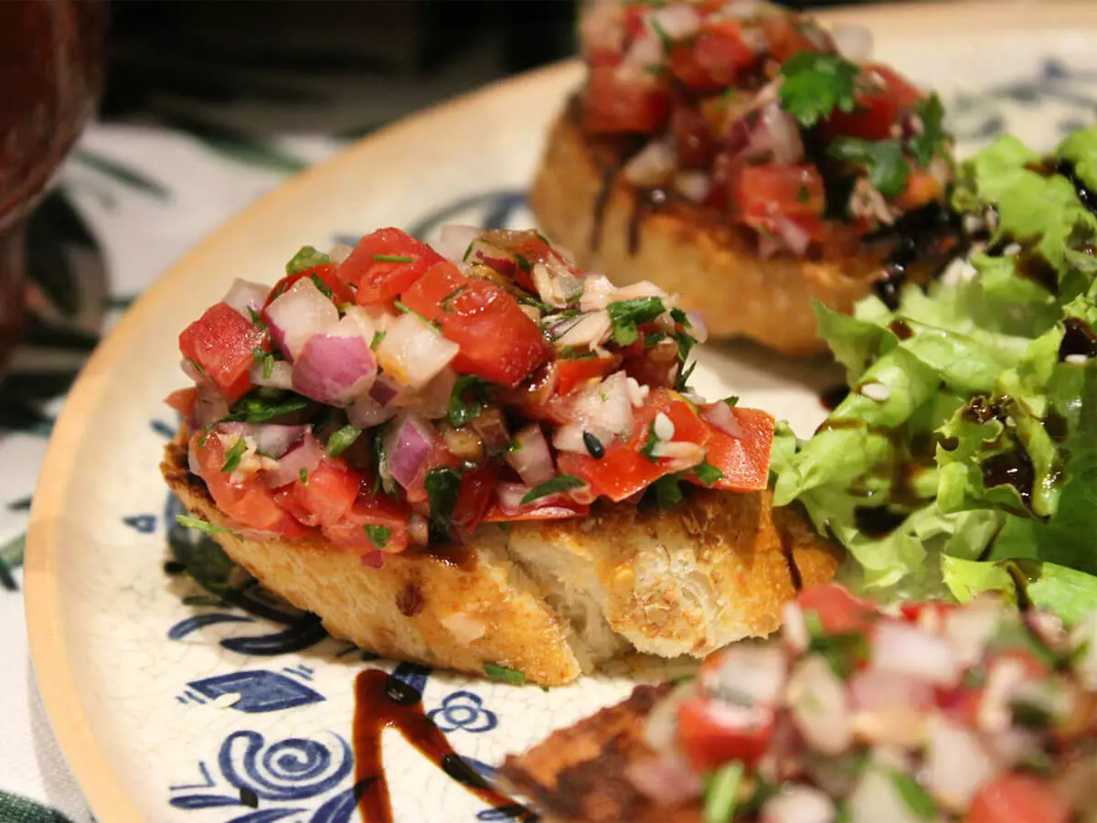 Bruschetta-Brote mit Salatbeilage auf einem Teller.