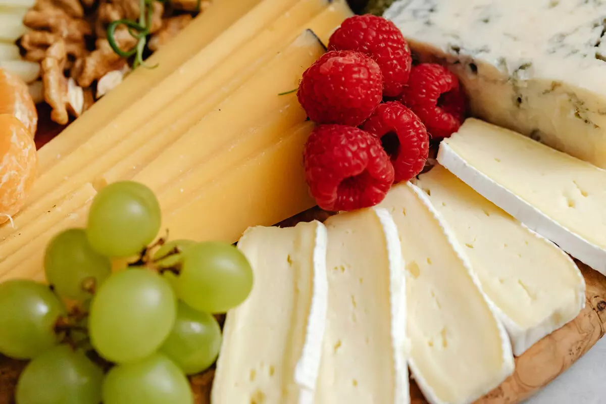 Snackboard mit Käsevariationen, Himbeeren und Weintrauben.