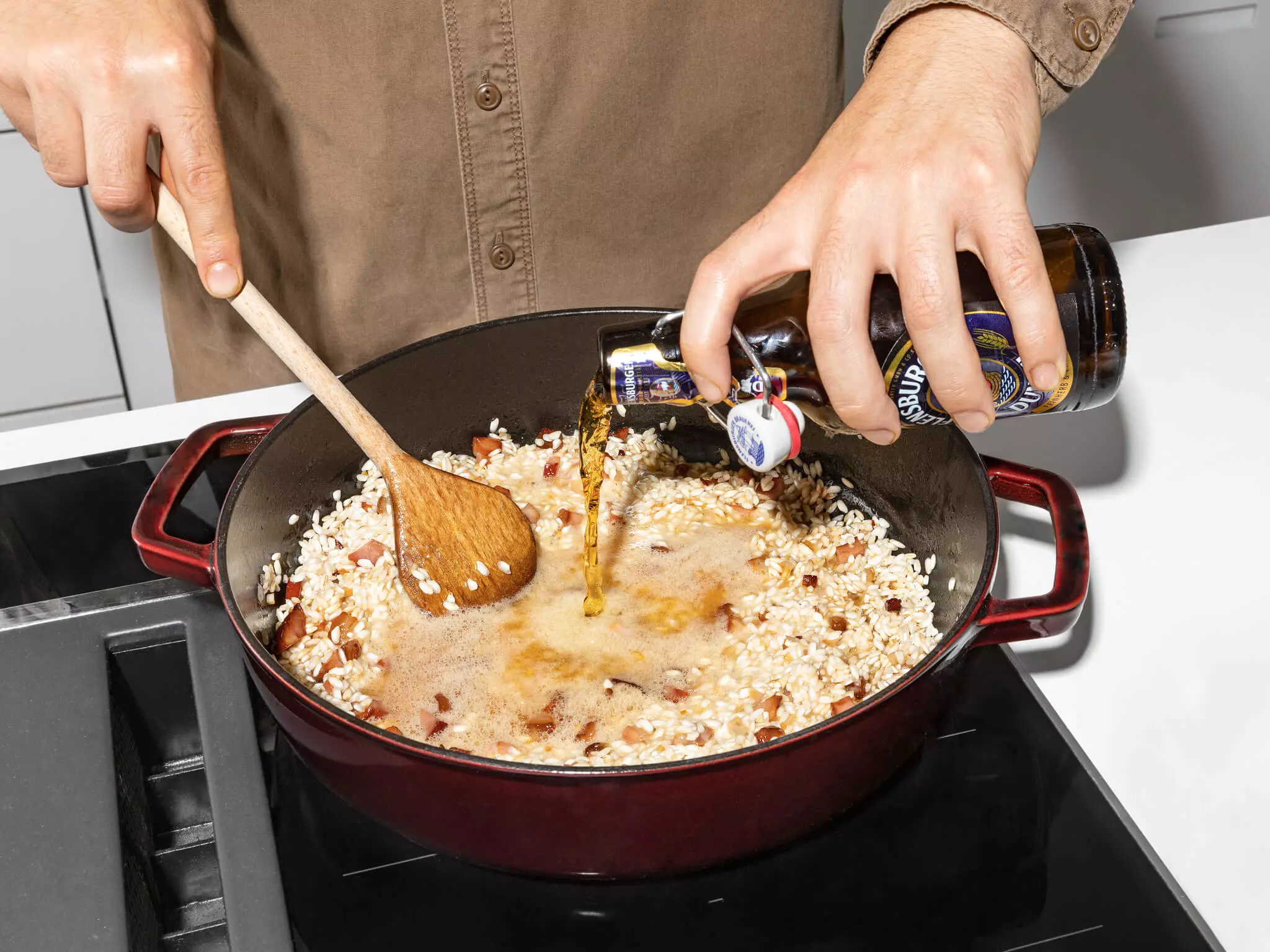 FLENS Dunkel, das in eine Pfanne mit Risotto gegeben wird.