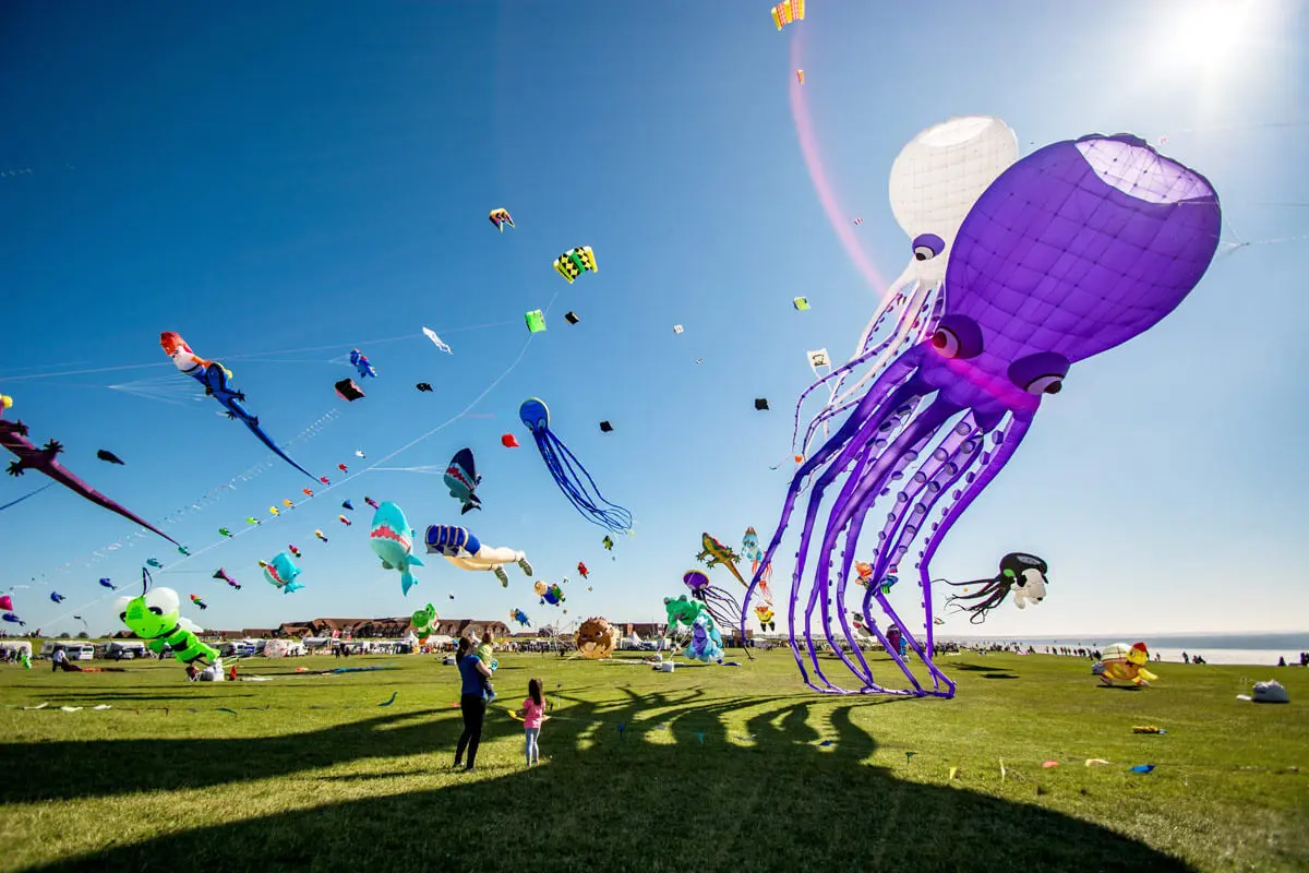 Buntes Drachenfest am Meer in Norddeich mit riesigem violetten Oktopus-Luftdrachen und zahlreichen farbenfrohen Kites.