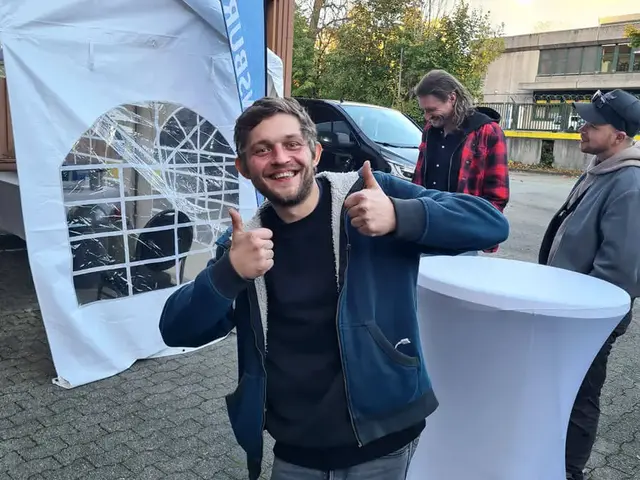 Der glückliche Gewinner gibt Daumen hoch bei der Grillweltmeisterpary von FLENS mit Zelt und Beachflag im Hintergrund.