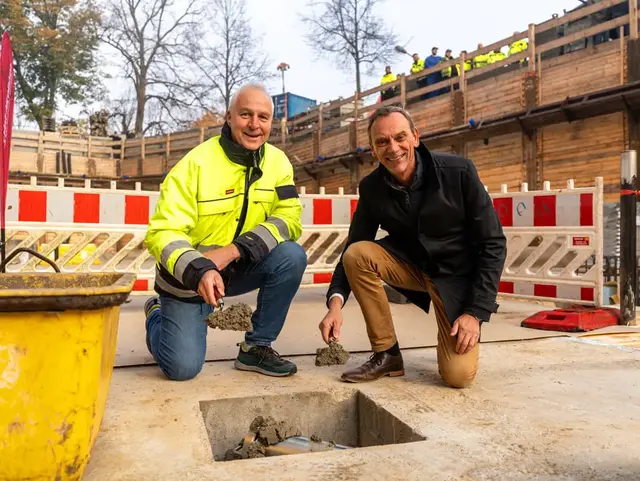 Die Geschäftsführer der Flensburger Brauerei posieren mit Betonkelle vor der einbetonierten Zeitkapsel.
