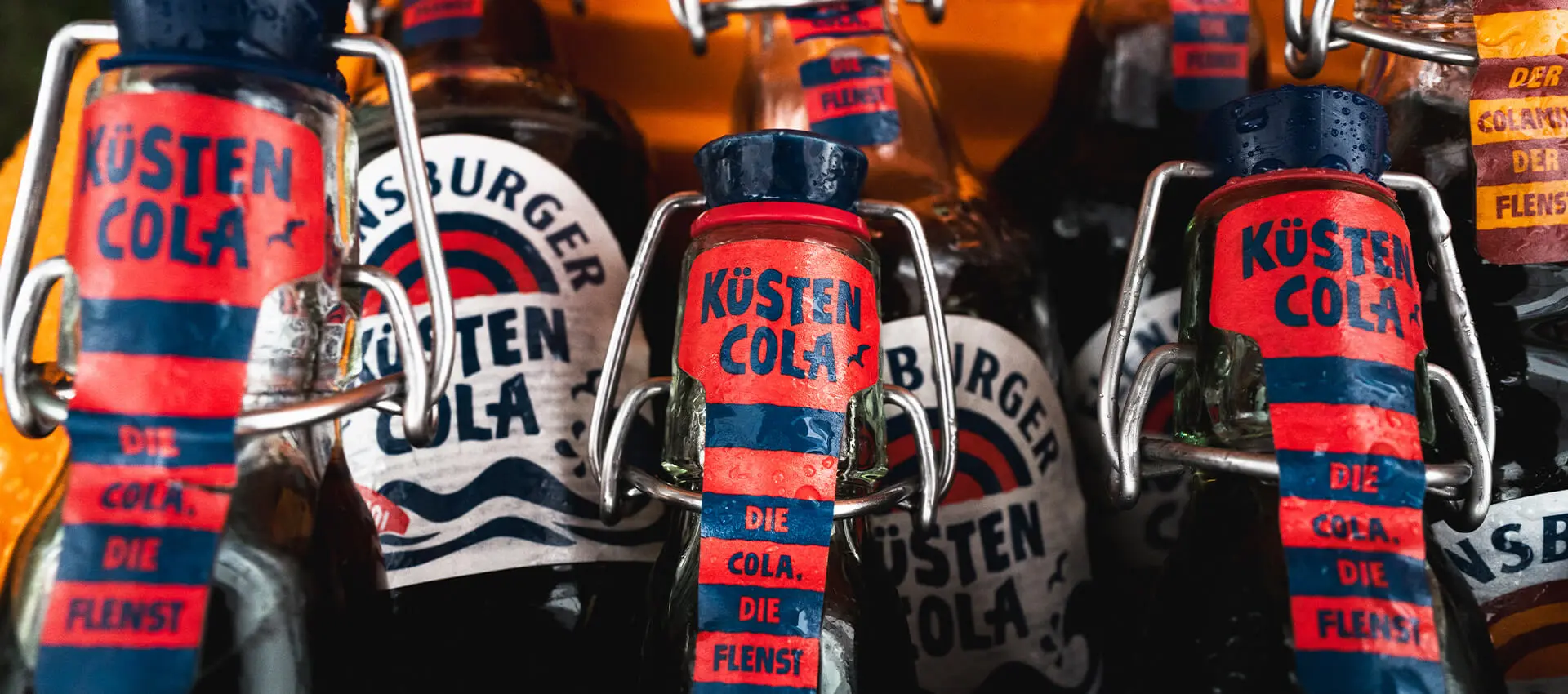 Küstencola-Glasflaschen mit Bügelverschluss und roten Etiketten, Nahaufnahme.