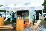 Der gesamte Auftritt des Küstenlimo-Promo-Vans mit Stehtischen, Sonnenschirmen, Loungemöbeln und Surf-Übungsbrett.