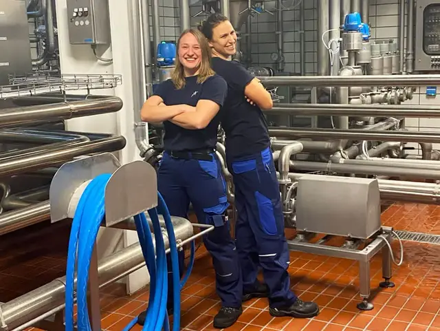 Die Brauerinnen Lisa & Karolin von FLENS stehen Rücken an Rücken im Gärkeller.
