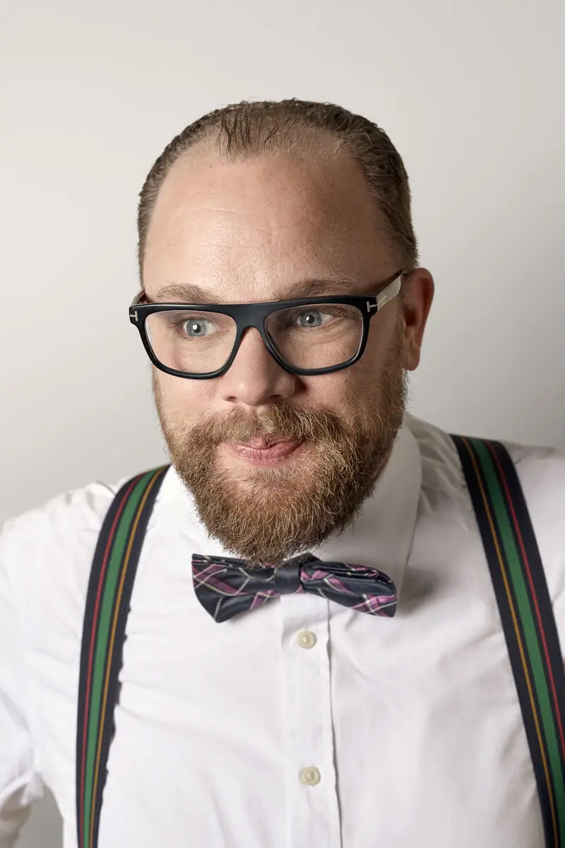 Porträt von Jan Bergmann von Steinbeis im weißen Hemd mit gemusterter Fliege und gestreiften Hosenträgern.