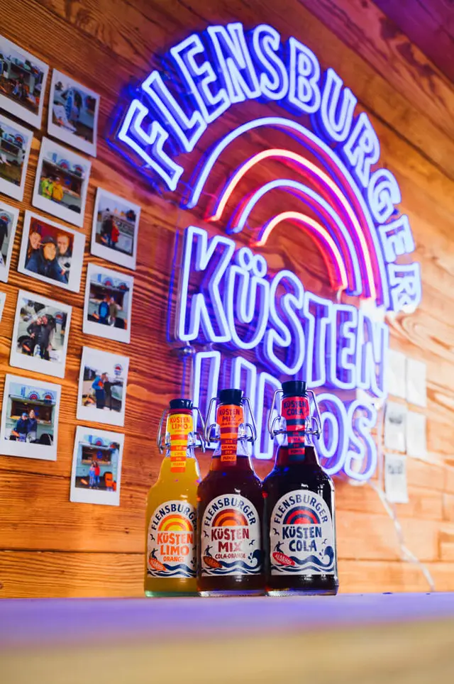 Die Flensburger Küstenlimos vor einem Leuchtschild.