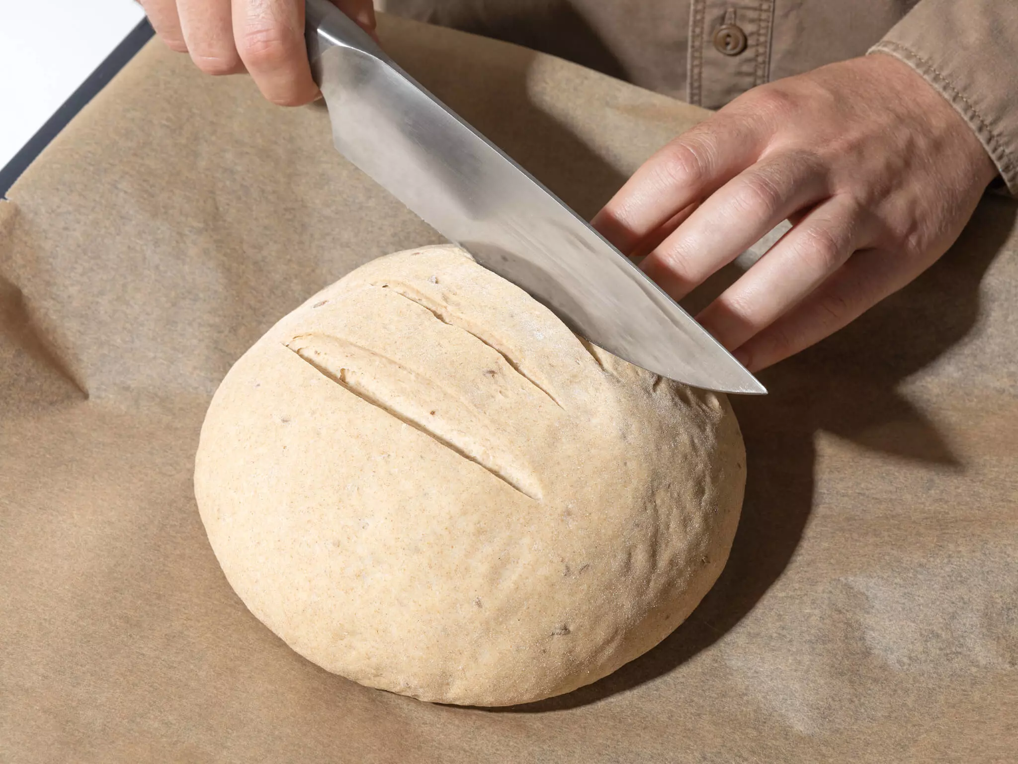 Ungebackenes Brot, das eingeschnitten wird. 