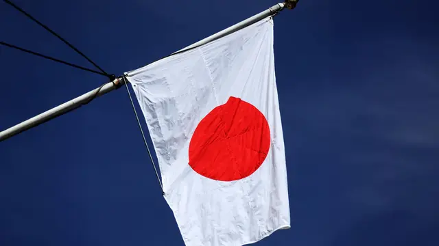 Die gehisste Flagge Japans vor blauem Himmel.