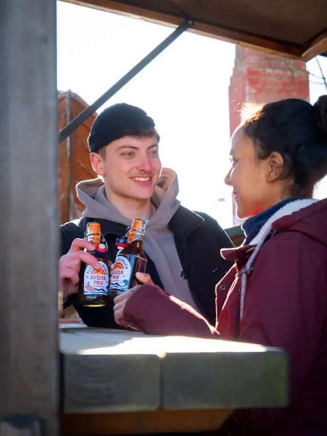 2 Menschen stoßen mit den Küstenmixen an.