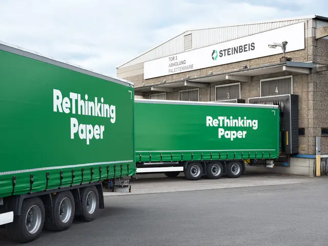 Grüne Lkw-Anhänger mit ReThinking Paper-Schriftzug beim Verladen an Steinbeis-Logistikhalle.