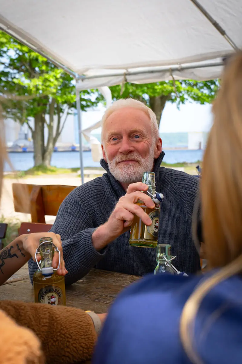 Andreas Arndt mit Flaschenbier beim geselligen Outdoor-Picknick am Wasser.