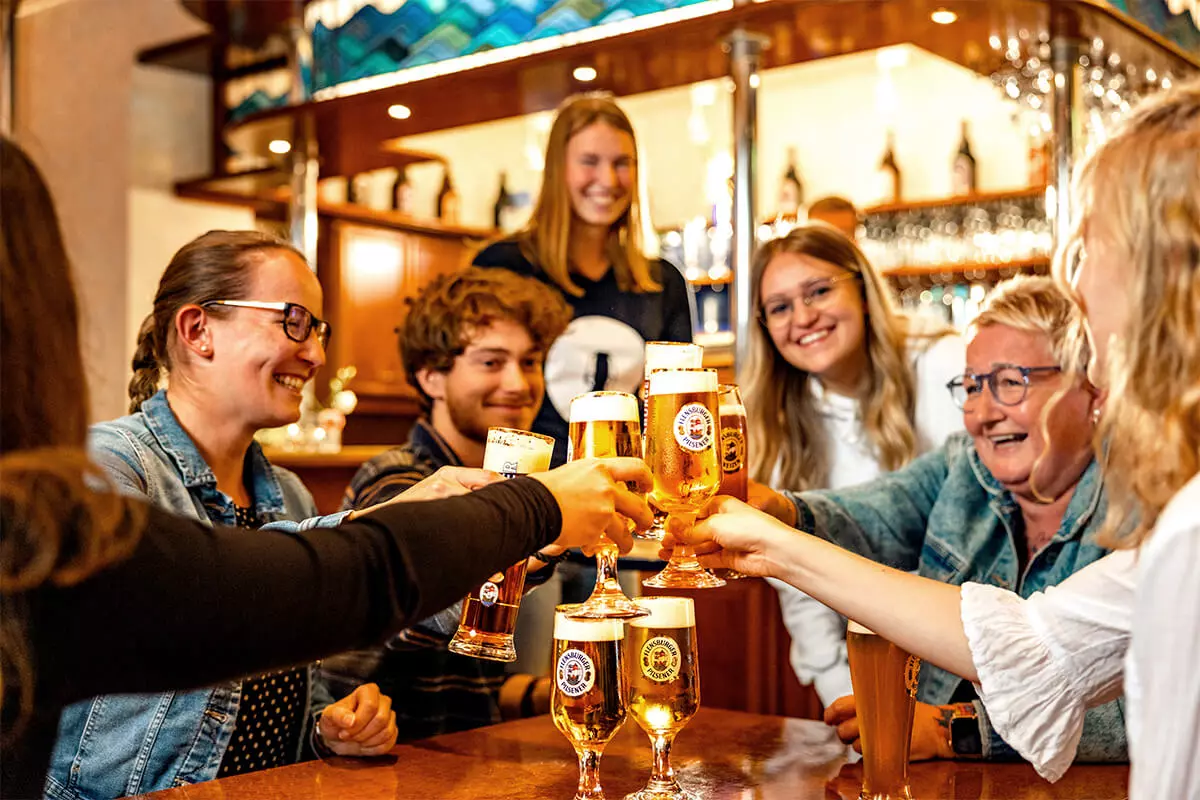 Eine Gruppe von Leuten stößt mit frisch gezapftem FLENS im Flensburger Salon an.