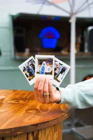 Polaroids werden in die Kamera gehalten, im Hintergrund der Küstenlimo-Promo-Van.