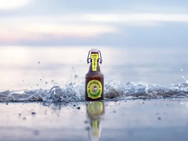 Eine Flasche Flensburger Frühlingsbock steht in der Brandung am Meer in der Welle.