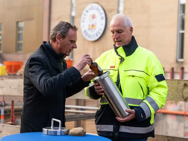 Die Geschäftsführer der Flensburger Brauerei befüllen die Zeitkapsel mit einer Flasche Flensburger Pilsener.