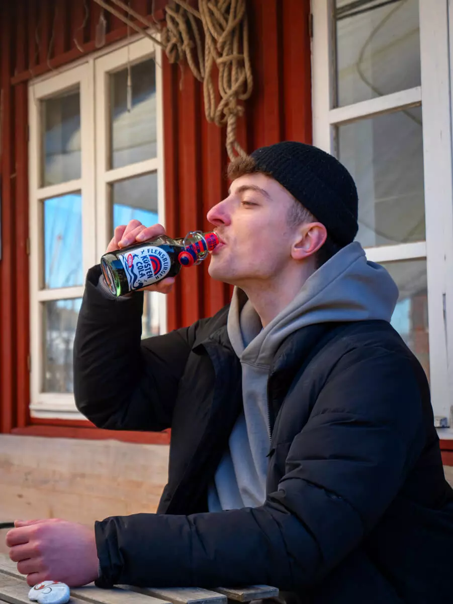 Ein Mann trinkt einen Flensburger Küstenmix am Hafen.