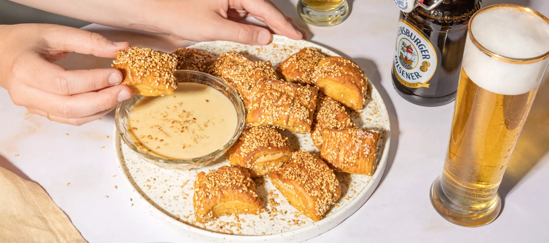 Brezel Bites mit einem FLENS Pils in der Flasche und im Glas. 
