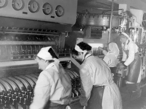 Historische Aufnahme von Frauen am Arbeiten an der Flaschen-Waschanlage in der Abfüllung bei FLENS.