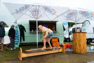 Ein Kind testet seine Surfskills auf einem Übungsboard vor dem Küstenlimo-Promo-Van.