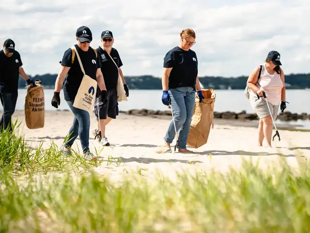 Gruppe von Leuten sammelt Müll am Strand bei einer FLENS StrandGut-Aktion.